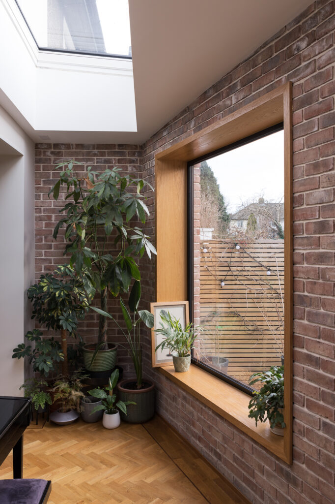 brick-lined-wall-with-timber-framed-window-and-plants-in-ceramic-pots