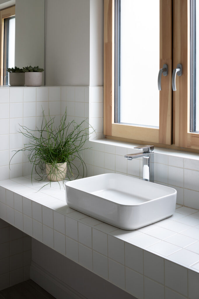 white-porcelain-sink-on-white-tiled-counter-with-potted-plants