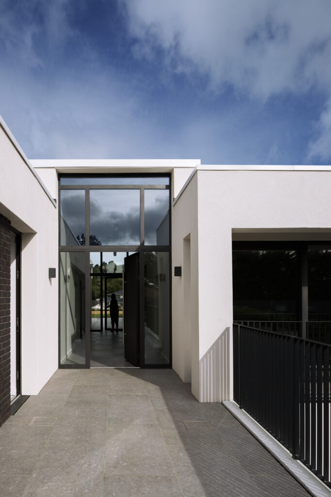 glazed-entrance-to-modern-white-villa-with-silhouetted-figure-in-hallway