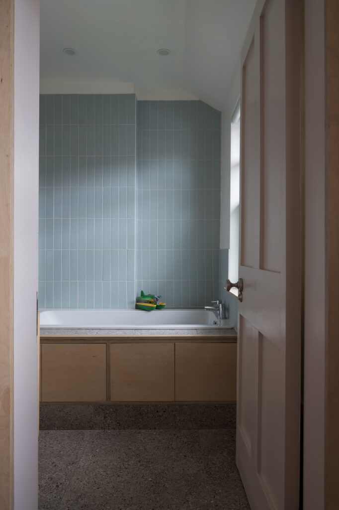 plywood-clad-bath-with-blue-tiled-wall-and-tiled-floor