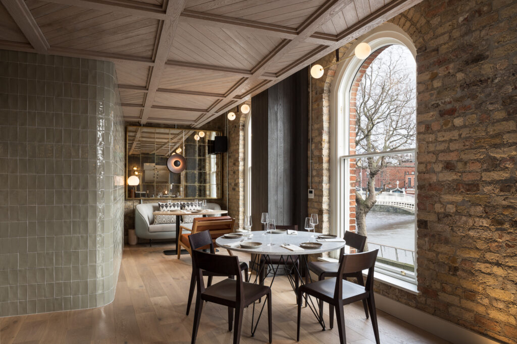 round-set-table-at-restaurant-with-tiled-mirrored-and-brick-walls-and-view-of-the-ha'penny-bridge