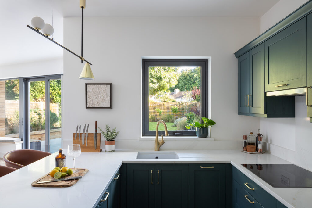 blue-and-white-kitchen-with-views-to-garden-and-gin-on-cutting-board-with-knife-and-lemon-and-limes