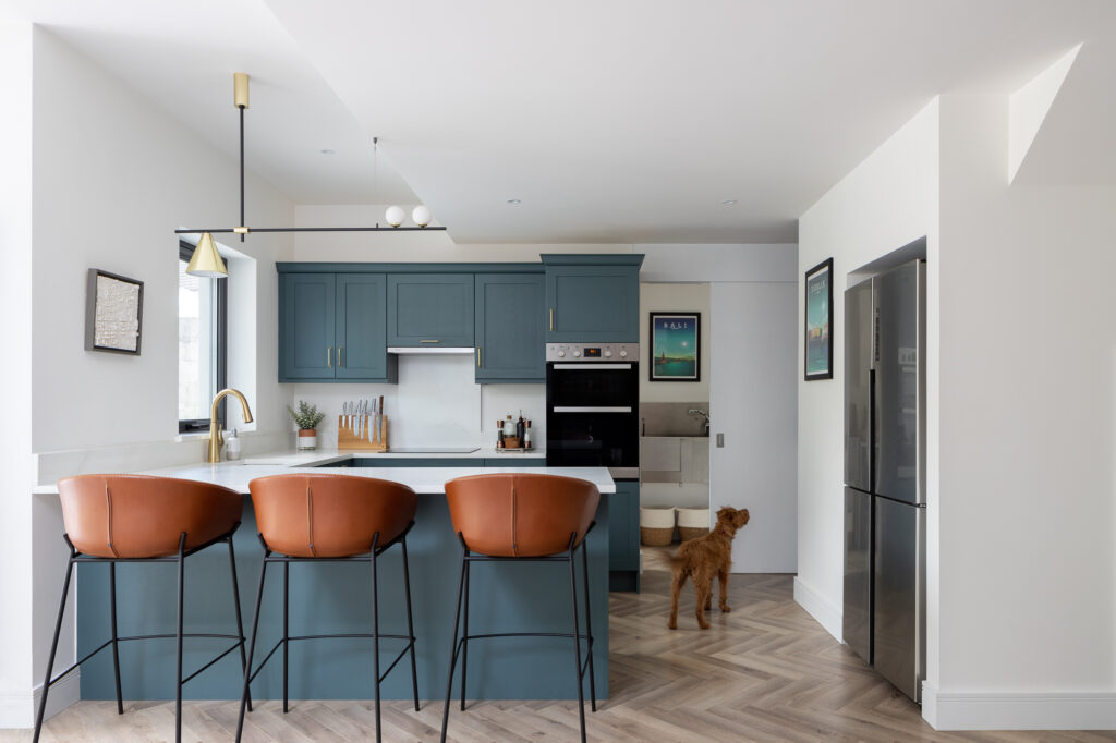 blue-and-white-kitchen-with-wooden-floor-and-brown-leather-stools-with-dog