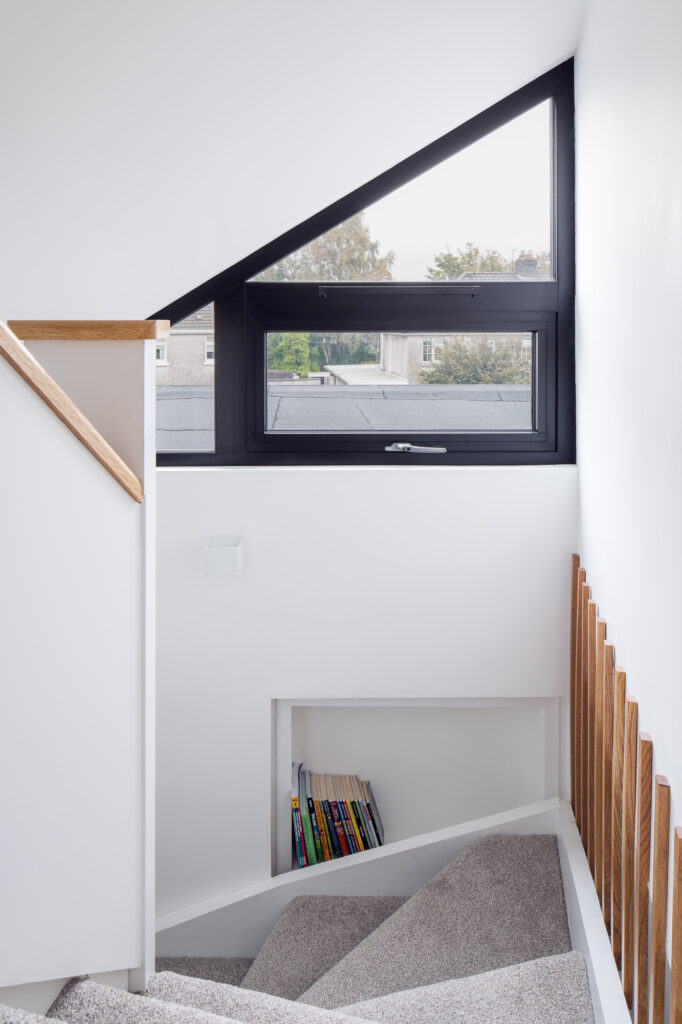 white-winder-stairs-with-inbuilt-bookshelf-and-triangular-window