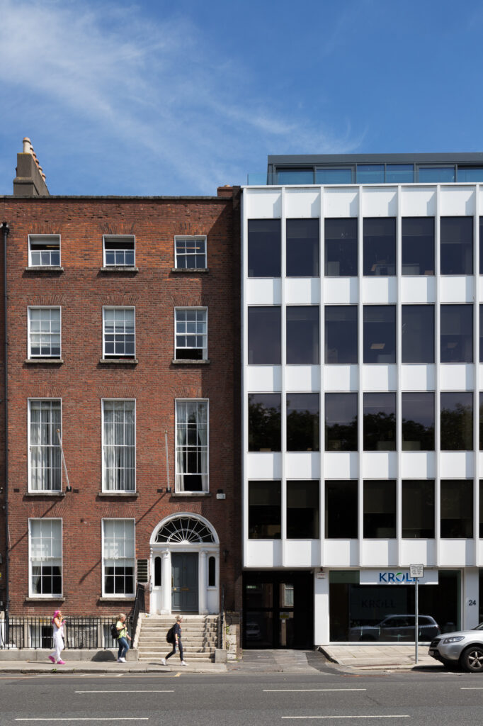 white-elevation-of-six-storey-lisney-building-beside-four-storey-red-brick-georgian-building-in-front-of-stephens-green-as-three-people-walk-by