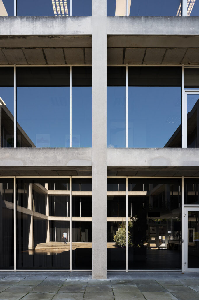 zichtbaar-beton-en-reflecterend-glas-structuur-reflecteert-courtyard-als-man-in-t-shirt-doorloopt