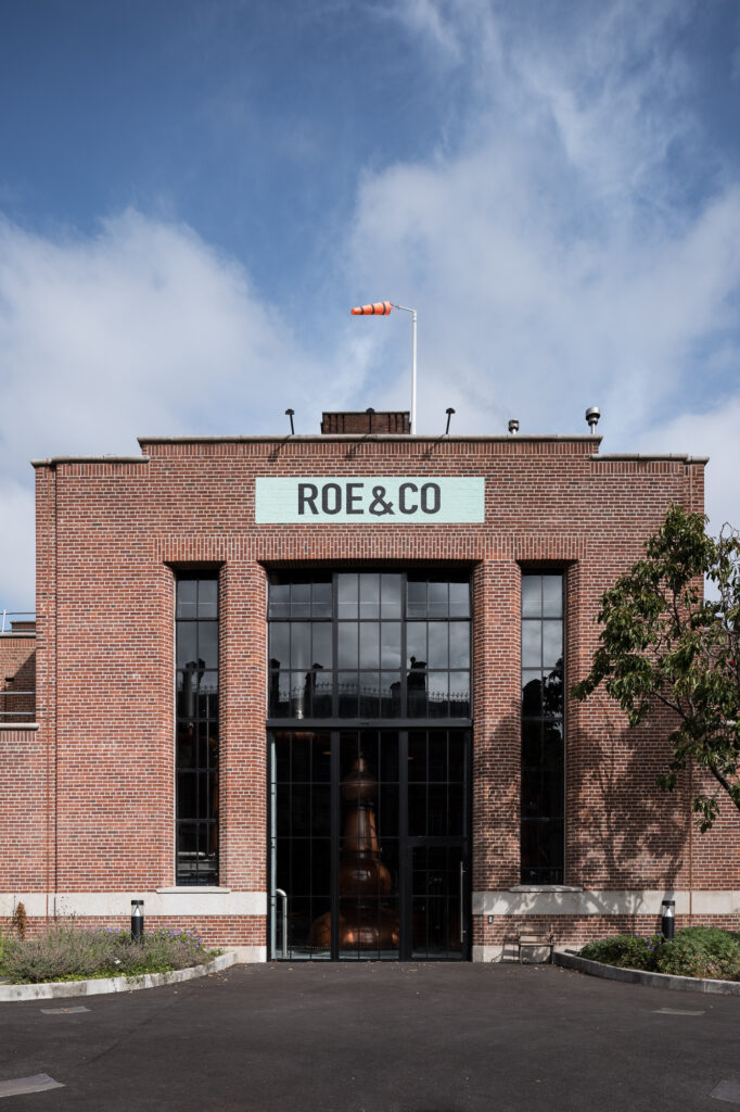 entrance-of-red-brick-former-power-plant-roe-&-co-distillery-with-distilling-pot-behind-glazing