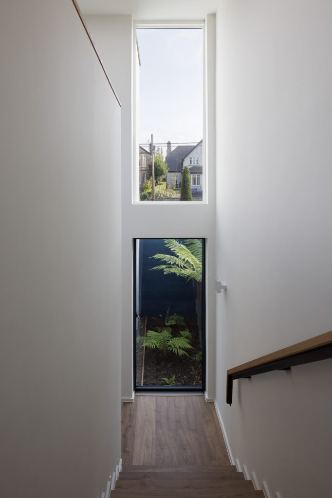 white-double-height-stairway-with-two-windows-to-courtyard-and-street