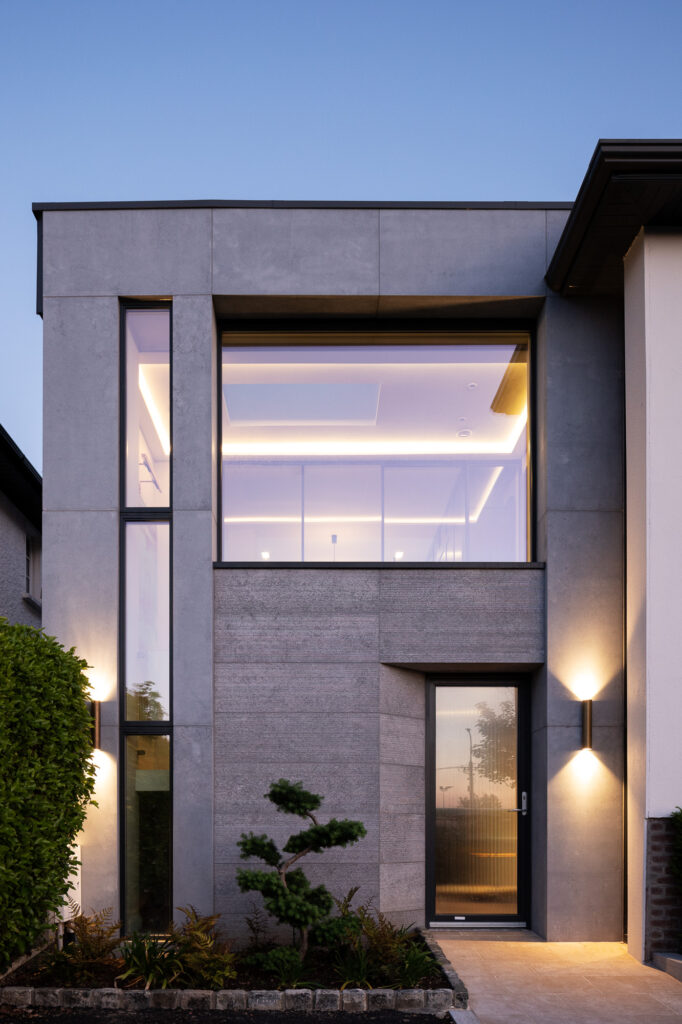 textured-concrete-and-limestone-clad-front-elevation-at-twilight