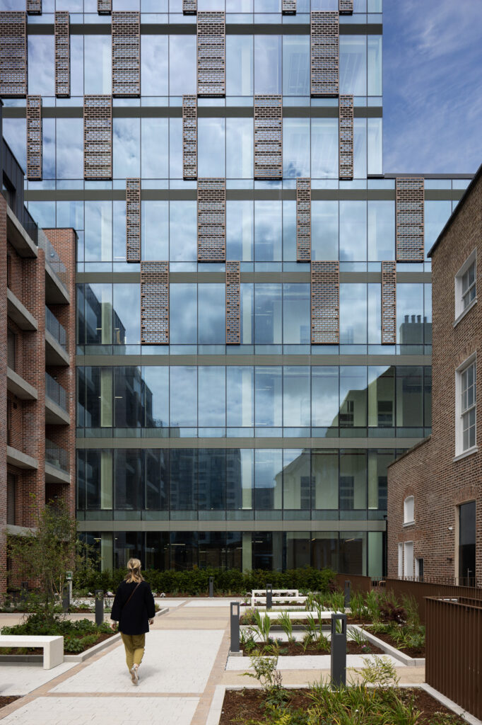 woman-walking-through-courtyard-of-glass-and-brick-buildings