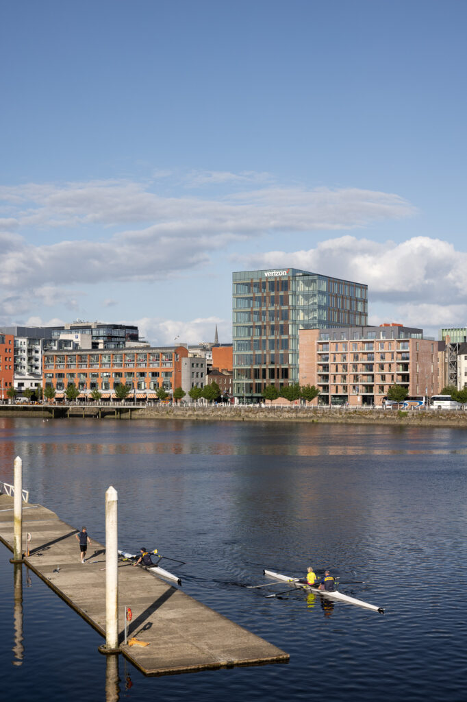 1bq-gebouw-van-over-de-shannon-rivier-in-limerick-met-roeiers-in-de-voorgrond