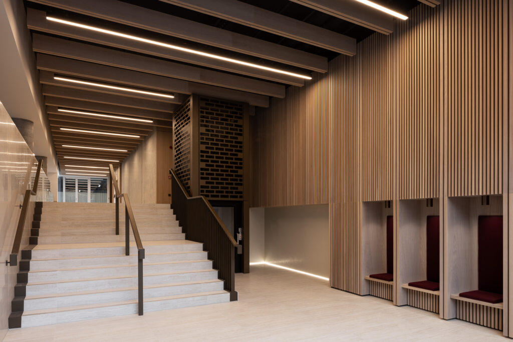 timber-clad-walls-with-inset-red-cushioned-seats-and-white-stone-stairs-of-entrance-hall