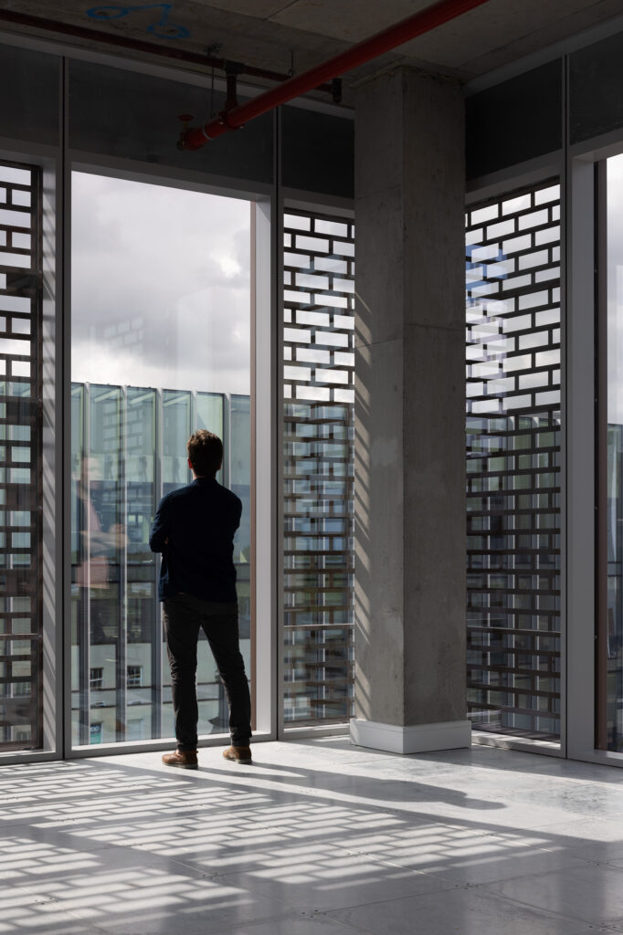 man-looking-out-windows-with-gridded-panels