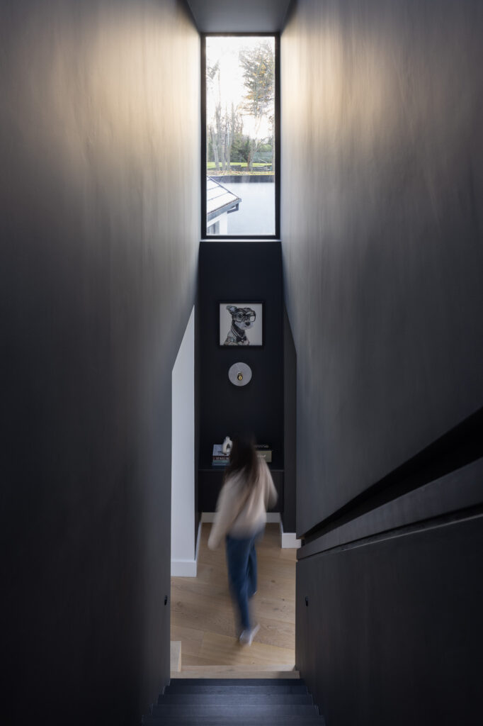 blurred-figure-of-woman-at-bottom-of-black-stairway-with-high-level-vertical-window