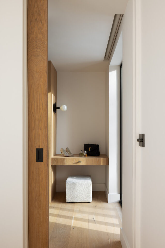 view-through-wooden-sliding-door-of-wooden-dressing-table-with-a-black-bag-sparkling-gold-shoes-and-perfumes-on-top