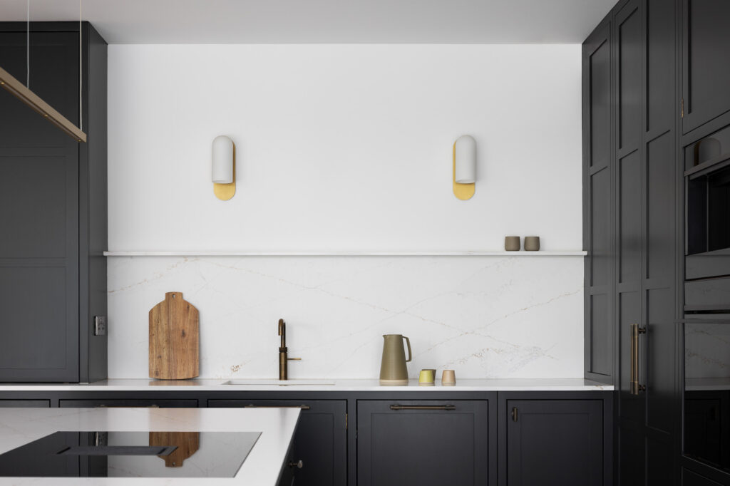 black-and-white-kitchen-with-wooden-chopping-board-and-clay-pastel-coloured-cups-and-jug-on-white-marble-counter-top