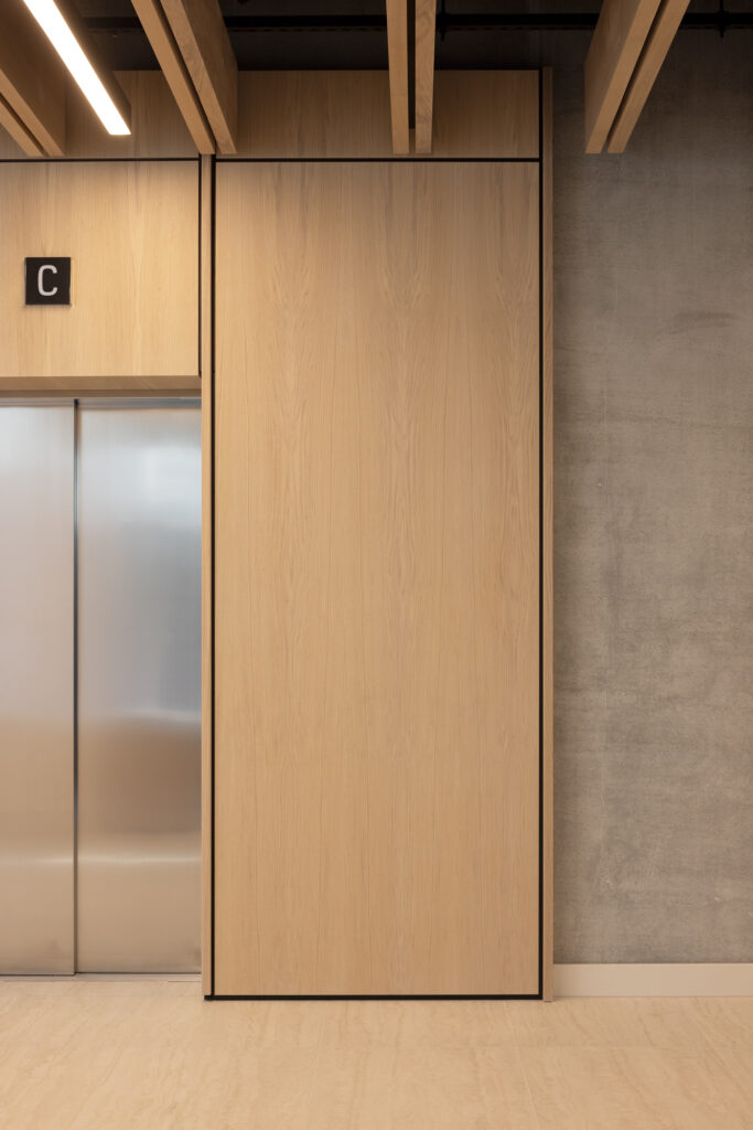 grey-steel-lifts-in-corridor-with-wooden-cladding-and-concrete-walls