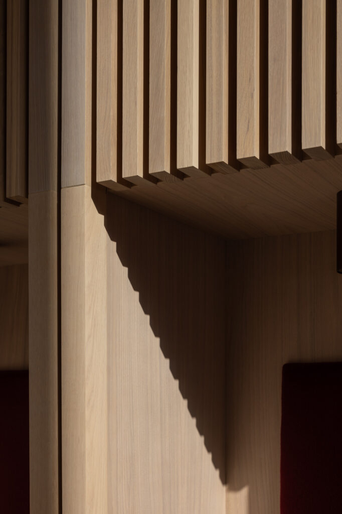 wooden-seat-corner-with-red-cushion-and-junction-highlighted-by-shaft-of-light-and-shadow