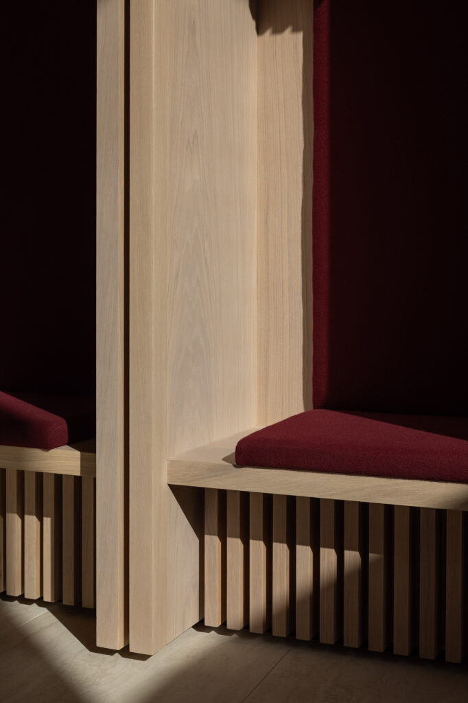 wooden-seat-corner-with-red-cushion-and-junction-highlighted-by-shaft-of-light