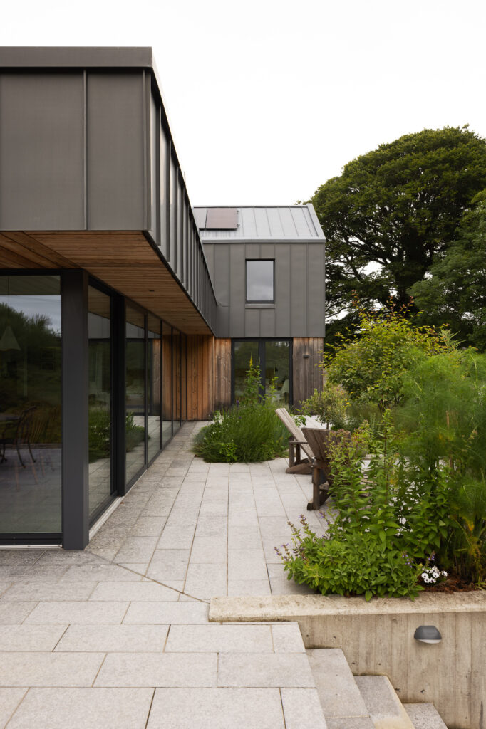 stone-patio-with-plants-deck-chairs-and-zinc-clad-residence-and-steps-to-lower-level