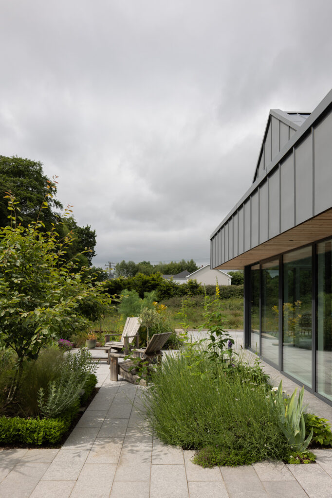 stone-patio-with-plants-deck-chairs-and-zinc-clad-residence