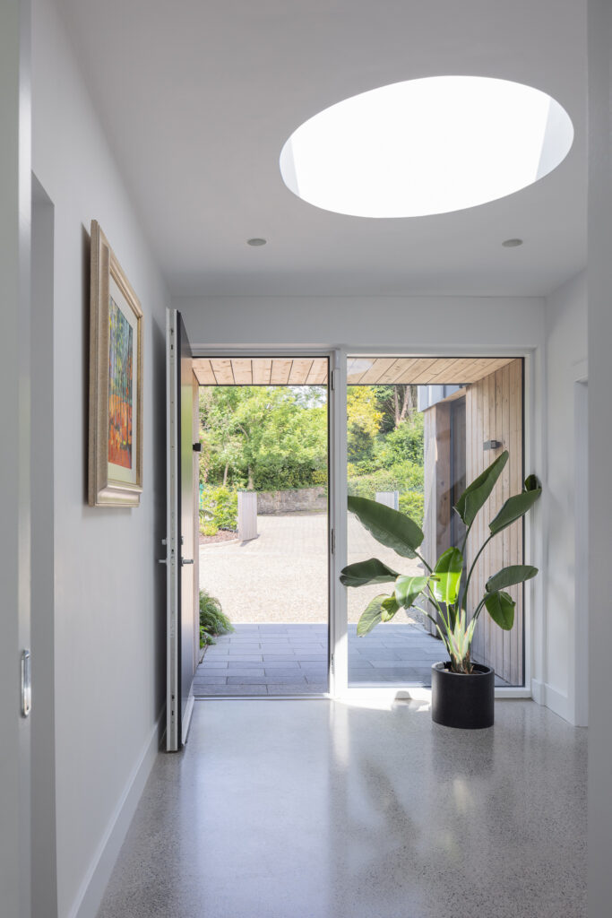white-walled-hallway-with-circular-roof-light-in-the-ceiling-and-open-door