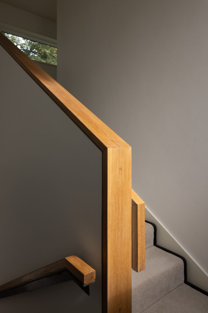 carpeted-stairway-with-wooden-handle-and-wooden-topped-balustrade
